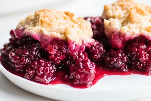 Two scoops of blackberry cobbler on a white plate