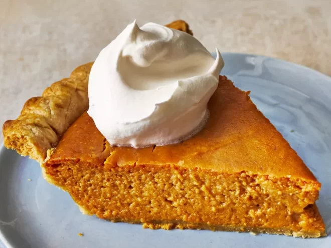 A slice of pumpkin pie with whipped cream on top