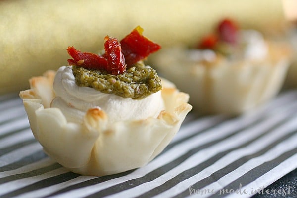 These Sun Dried Tomato, Pesto, and Garlic bite-size appetizers are perfect for parties. Creamy cheese in a phyllo cup, topped with sun dried tomato, pesto.
