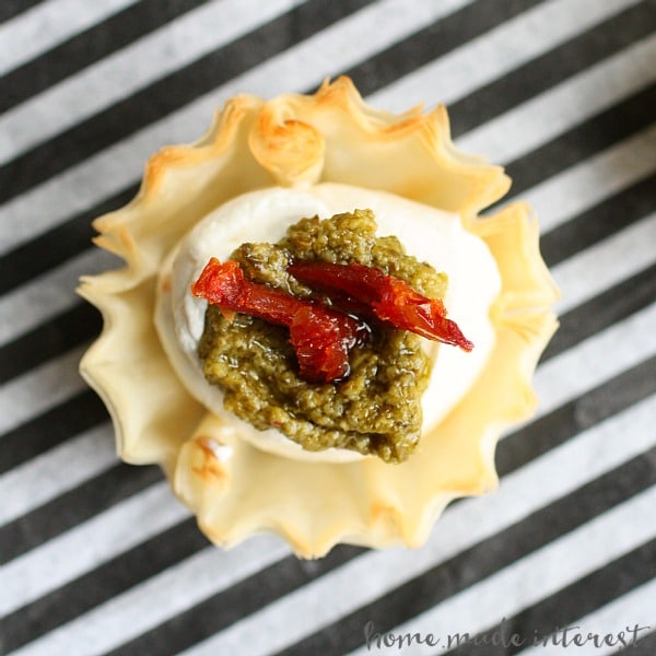 These Sun Dried Tomato, Pesto, and Garlic bite-size appetizers are perfect for parties. Creamy cheese in a phyllo cup, topped with sun dried tomato, pesto.
