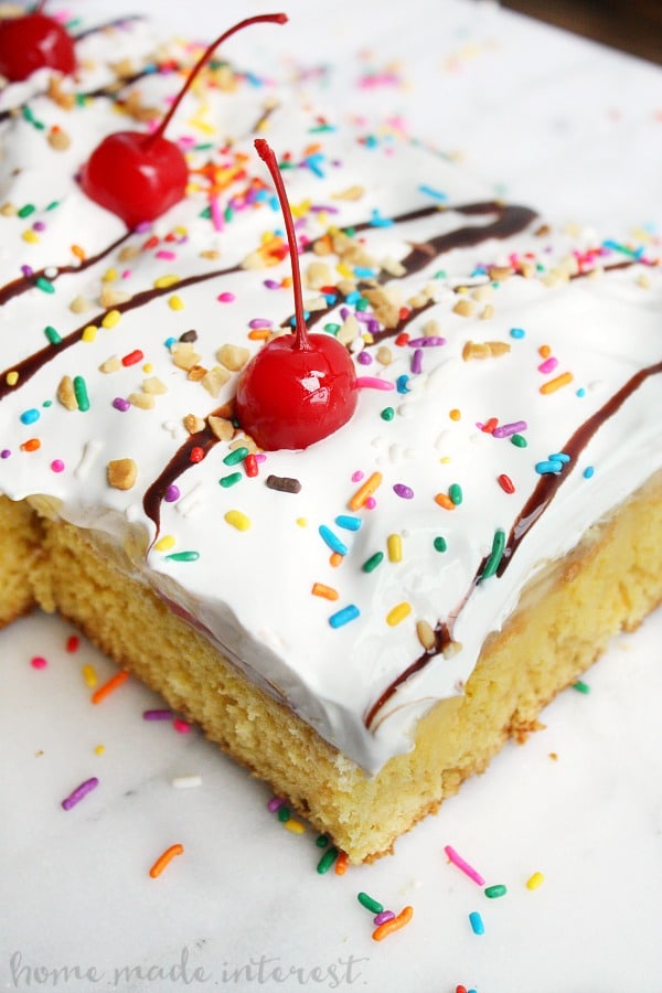 Have fun with this easy dessert recipe that kids and adults are going to love. All the flavors of a banana split in a poke cake recipe! Bananas, strawberries, and vanilla pudding covered in whipped cream, chocolate sauce and of course sprinkles with a cherry on top! This banana split poke cake recipe is easy and it is perfect for a birthday cake or a party.