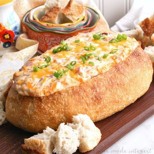 This decadent Mississippi Sin dip is an easy appetizer made with cheese and ham mixed together and baked inside a loaf of French bread until it is ooey gooey. The perfect game day appetizer or holiday party appetizer!