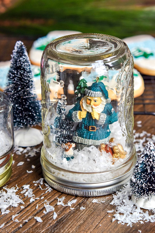 We have a simple tutorial for DIY Waterless Snow Globes made with mason jars. Mason jar snow globes are so much fun and these don’t require any water. We even made matching snow globe cookies that we decorated and served to the kids while we worked on our DIY snow globes!