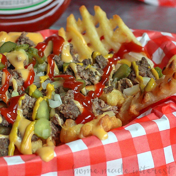 Loaded Cheeseburger Fries | These french fries are loaded with everything it takes to make a great cheeseburger. Ground beef, onions, pickles, cheese, and of course ketchup and mustard. Loaded Cheeseburger Fries are an awesome game day appetizer recipe for your next football party or a weeknight meal for the family. This loaded french fry recipe is going to blow your mind!