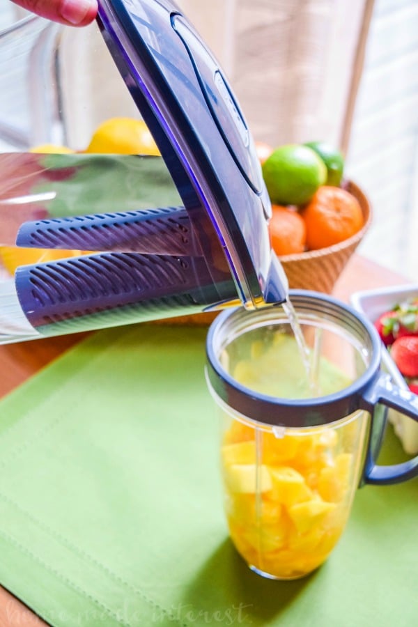 water being added to mango cubes for mango popsicles