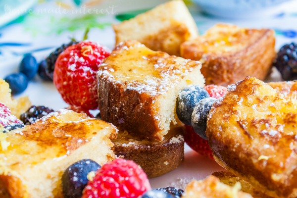 closeup of lemon poundcake french toast skewers with fresh berries and powdered sugar