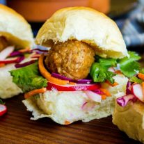 Single Banh Mi slider with meatball on pickled radish, carrots, cucumbers, and red cabbage.