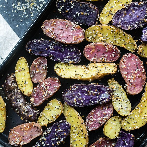 Sheet pan full of purple, pink, and yellow Everything Bagel Roasted Fingerling Potatoes