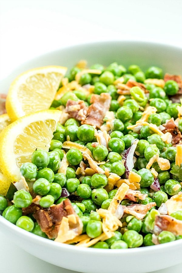 Creamy Bacon Pea Salad in a white bowl with lemon slices