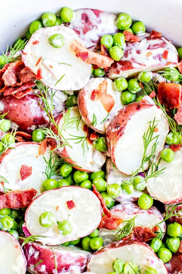 English Pea and Potato Salad with large crumbles of bacon, bright green peas, and creamy vinaigrette on red potatoes