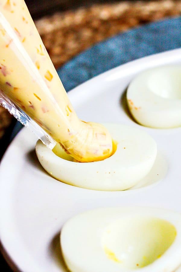 piping filling into the egg white half of a Mississippi Sin deviled egg
