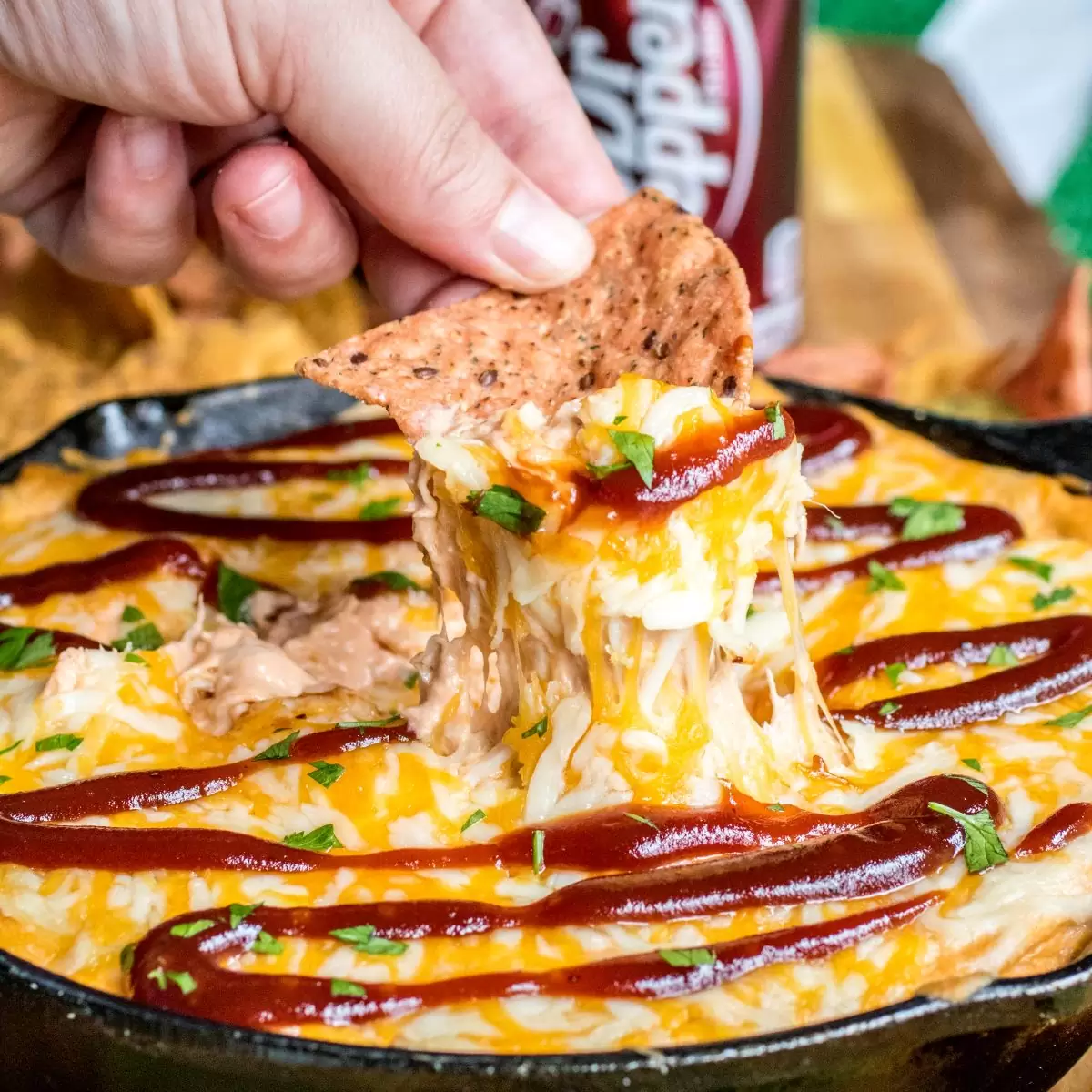 Chip scooping up Dr Pepper BBQ chicken dip.