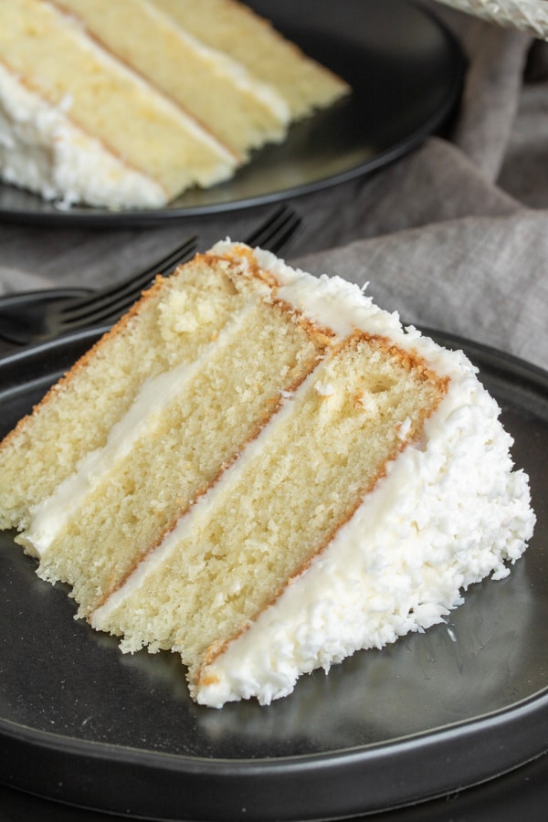 A slice of three layer coconut cake with fresh coconut