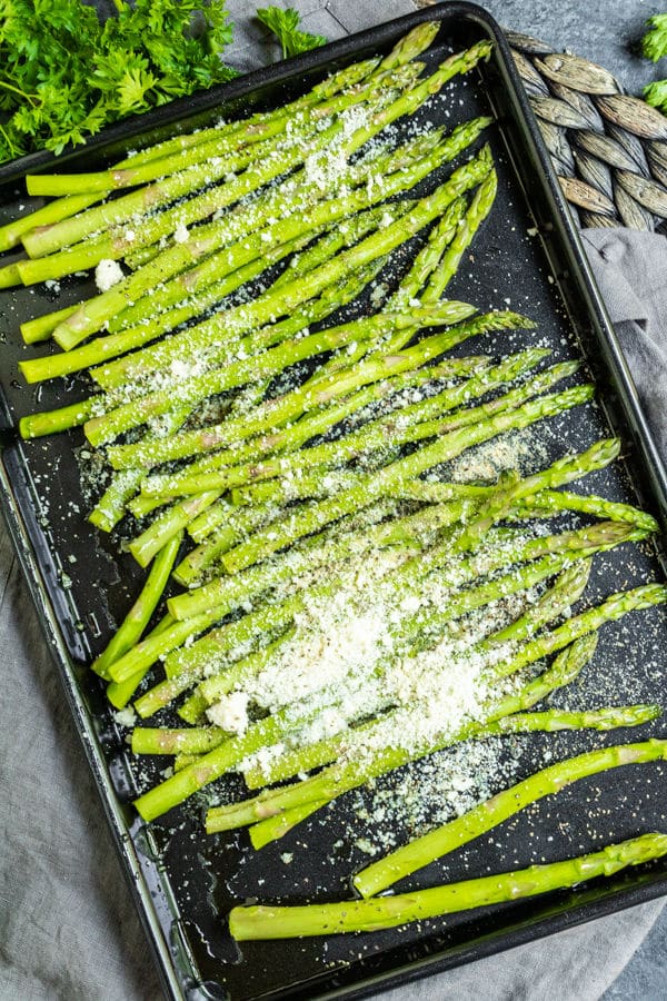 Air Fryer Asparagus seasoned with grated parmesan on a sheet pan