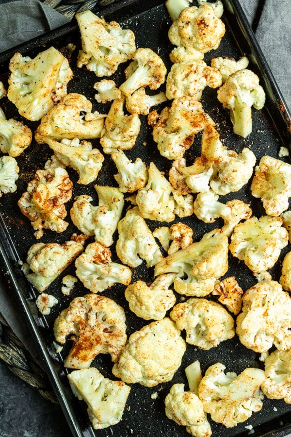 sheet pan of raw cauliflower tossed in spices