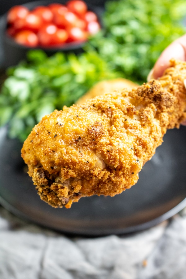holding a piece of Keto Fried Chicken in the Air Fryer
