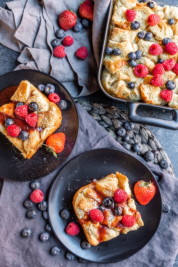 table with Overnight French Toast Bake on plates and platter topped with fresh berries