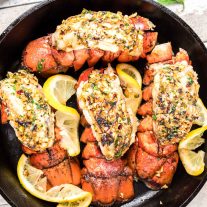 top down photo of broiled lobster tails in cast iron skillet