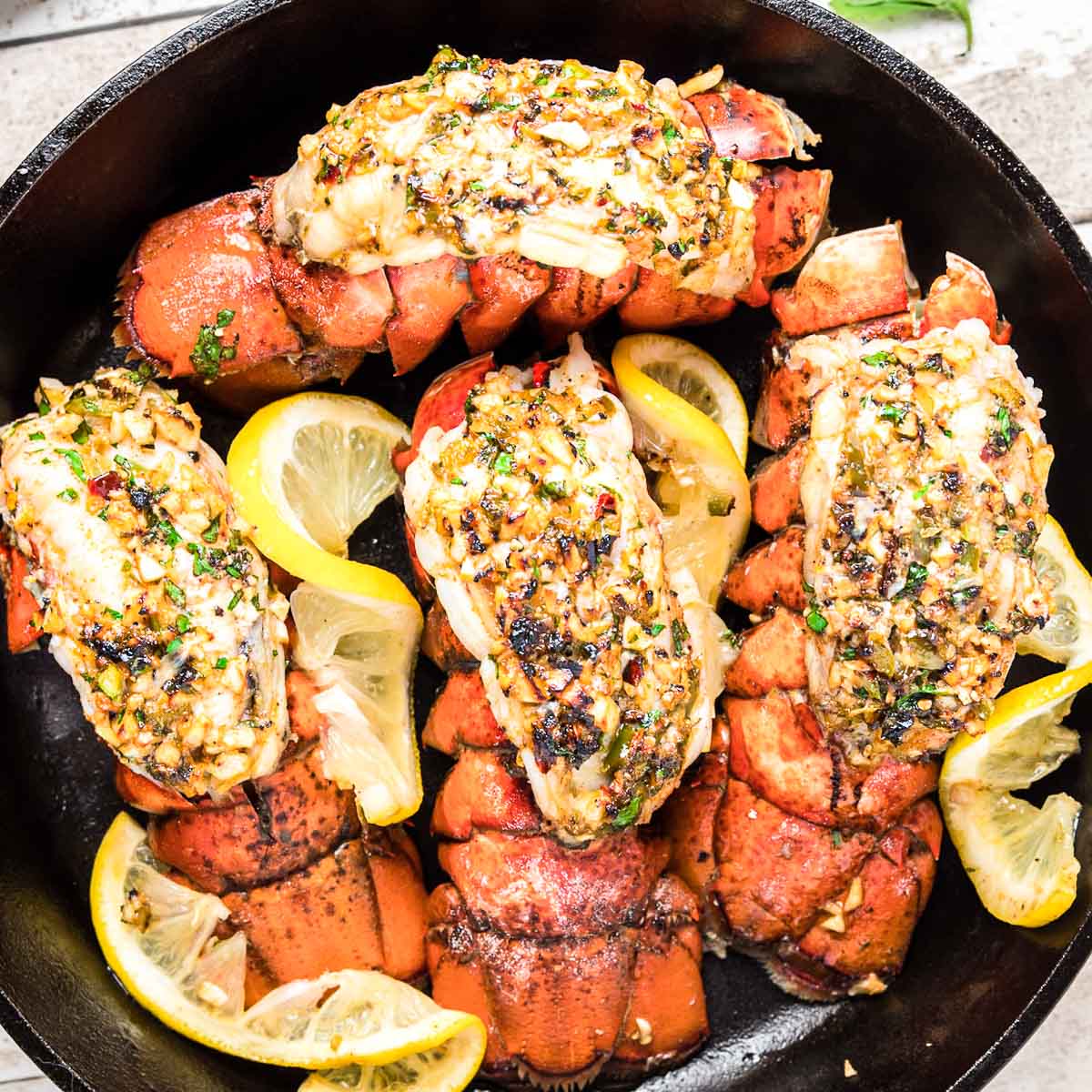 Top down photo of broiled lobster tails in a cast iron skillet