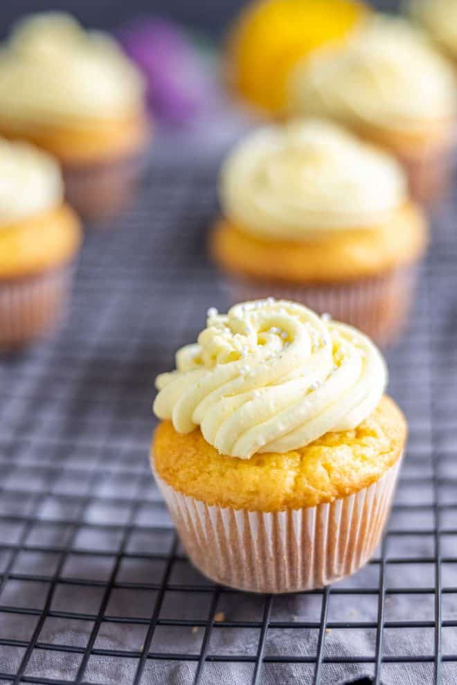 Lemon cupcake topped with a swirl of yellow lemon buttercream and white sprinkles