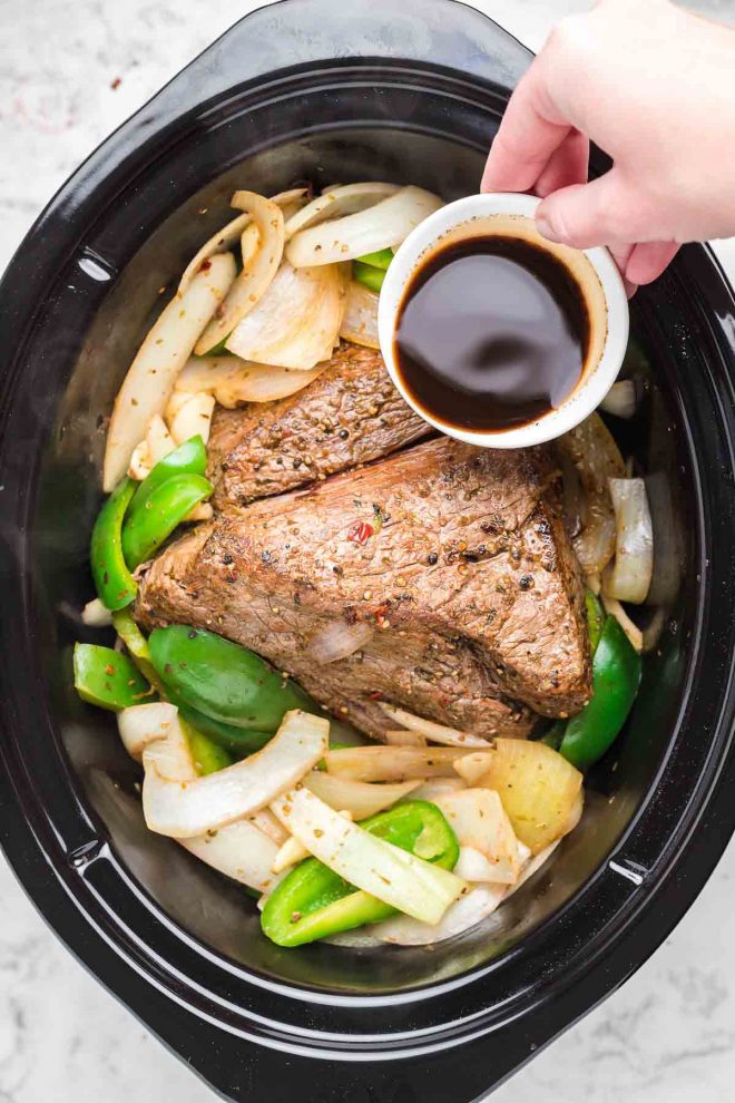 pouring sauce on Crock Pot Italian Beef on slow cooker