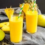 two Mango Pineapple Smoothie with pineapple wedges