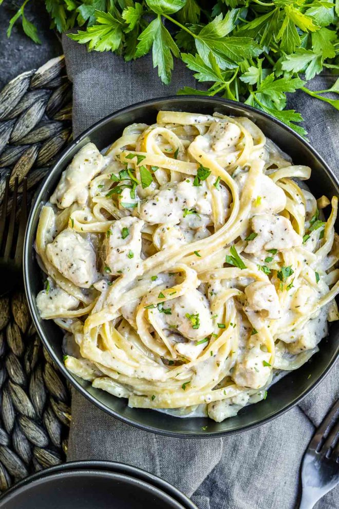 Instant Pot Chicken Alfredo in a black bowl garnished with parsley