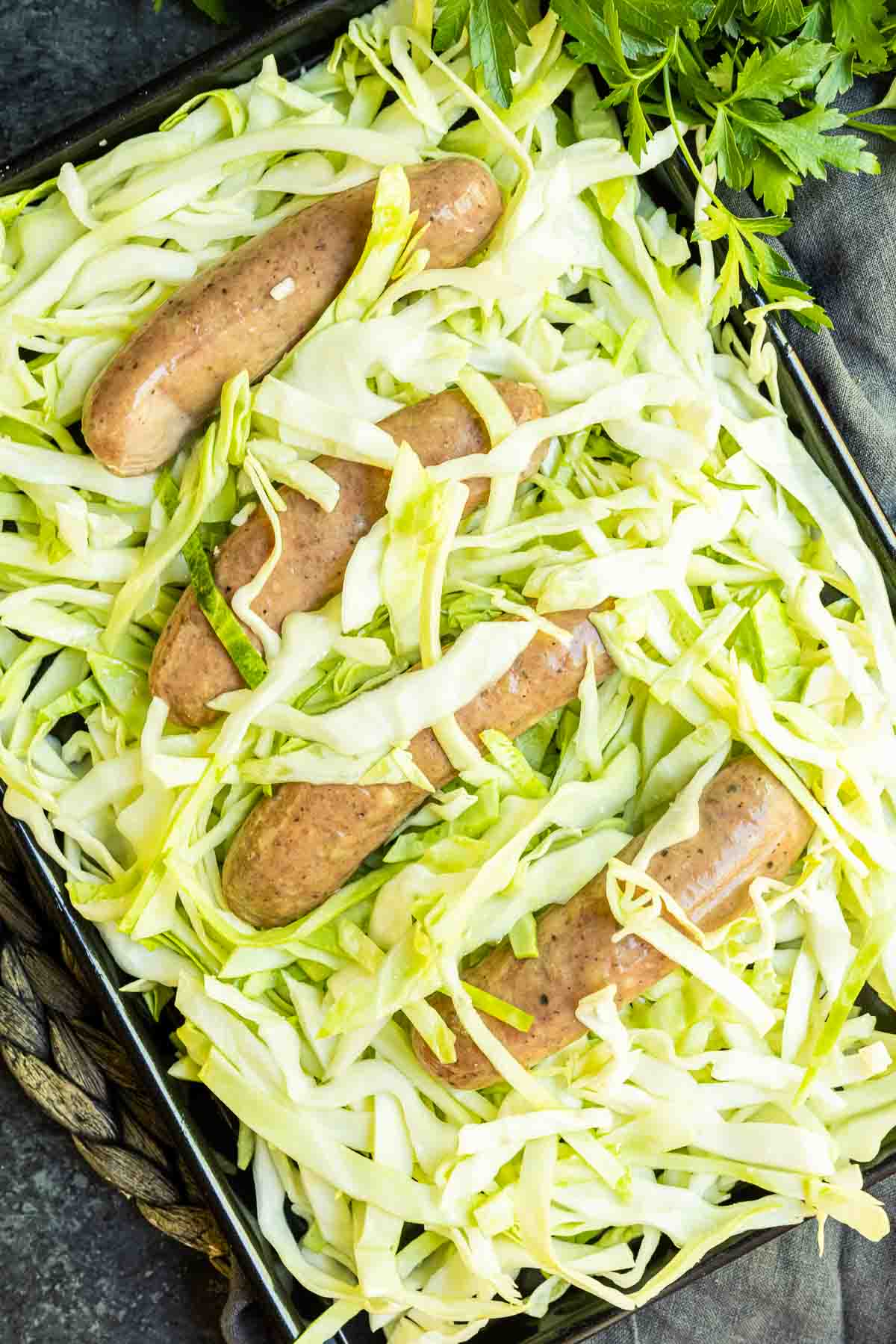 Sheet pan with uncooked cabbage and sausage