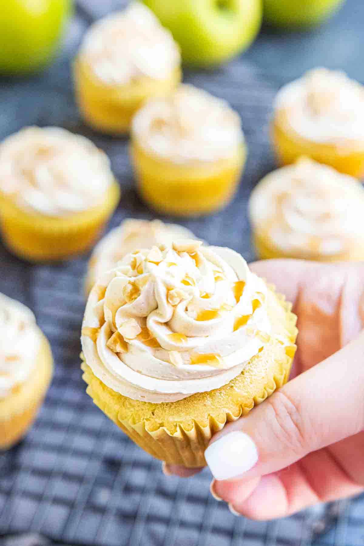Hand holding frosted caramel apple cupcakes