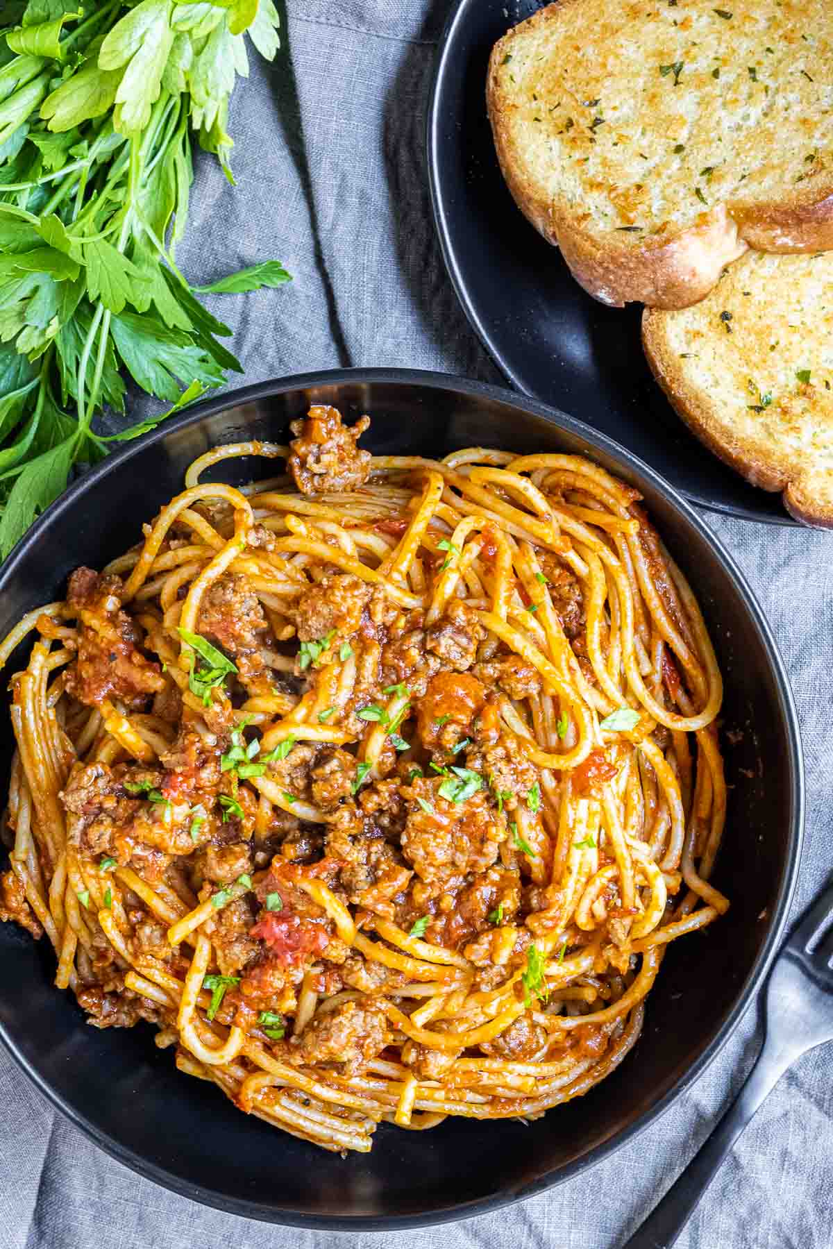 Instant Pot Spaghetti in a black bowl with garlic bread