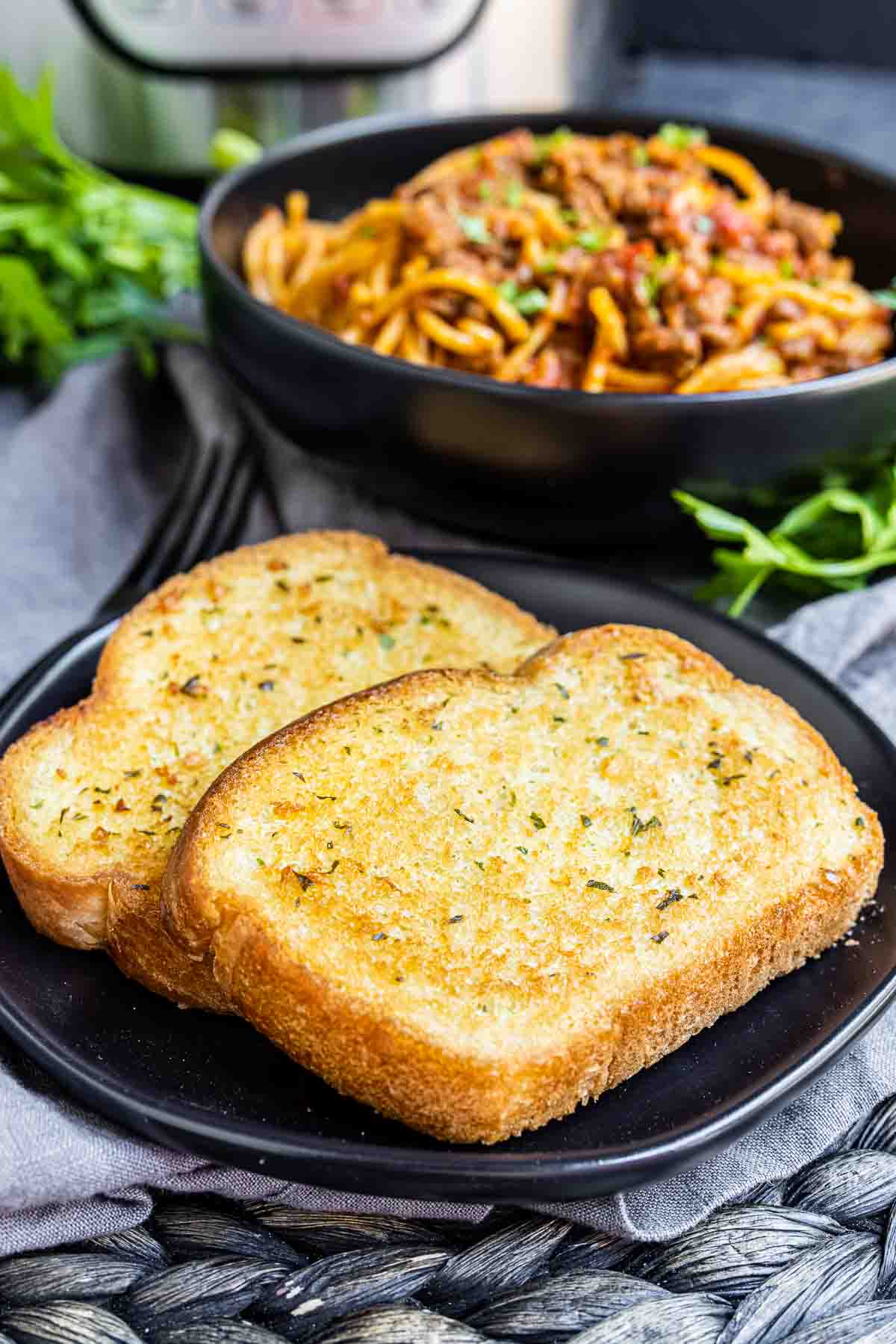 Texas Toast on a plate with spaghetti in a bowl