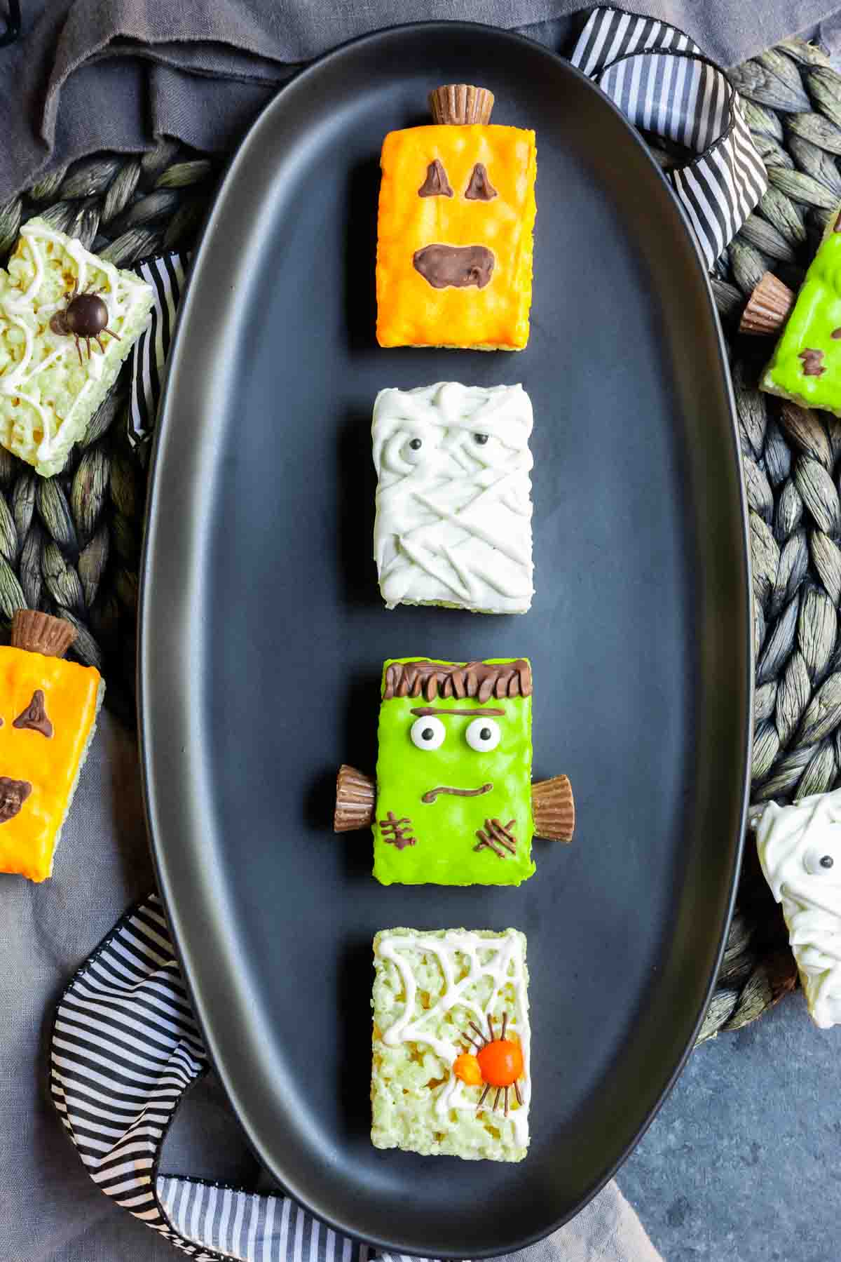4 Halloween Rice Krispies Treats styles, pumpkin, mummy, Frankenstein, and spider, on a black plate