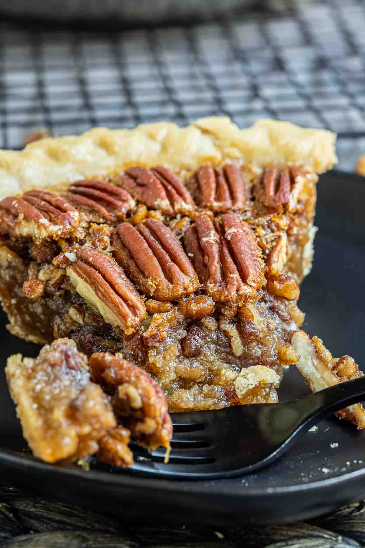 slice of pecan pie on a black plate with a black fork