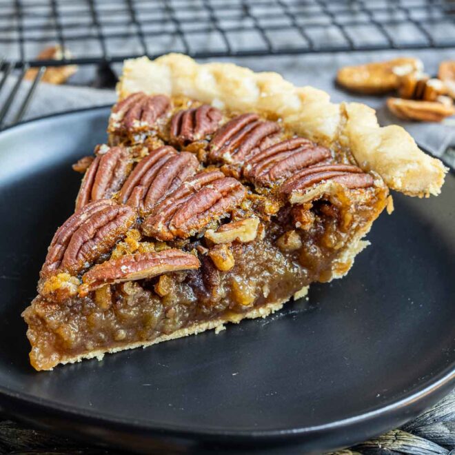 a slice of pecan pie on a black plate
