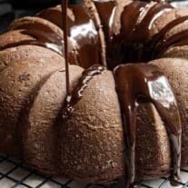 A chocolate bundt cake being drizzled with chocolate.
