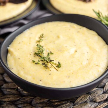 Creamy Polenta in a black bowl garnished with thyme