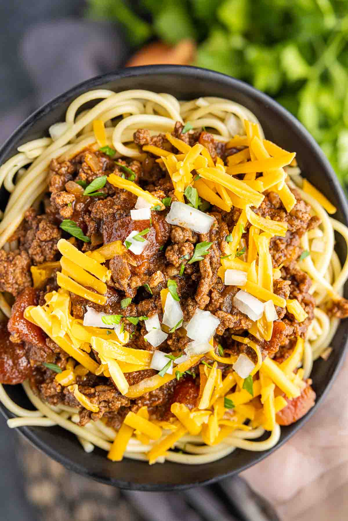 bowl of Cincinnati Chili topped with raw onions and shredded cheese