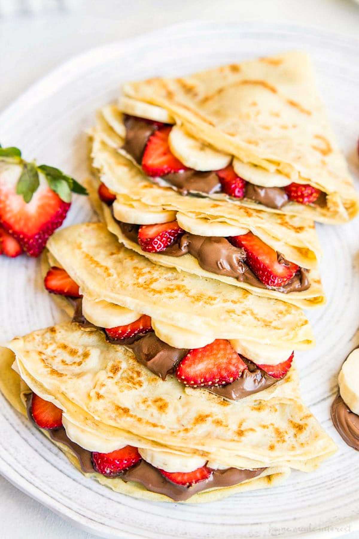 Nutella crepes in a line with bananas and strawberries