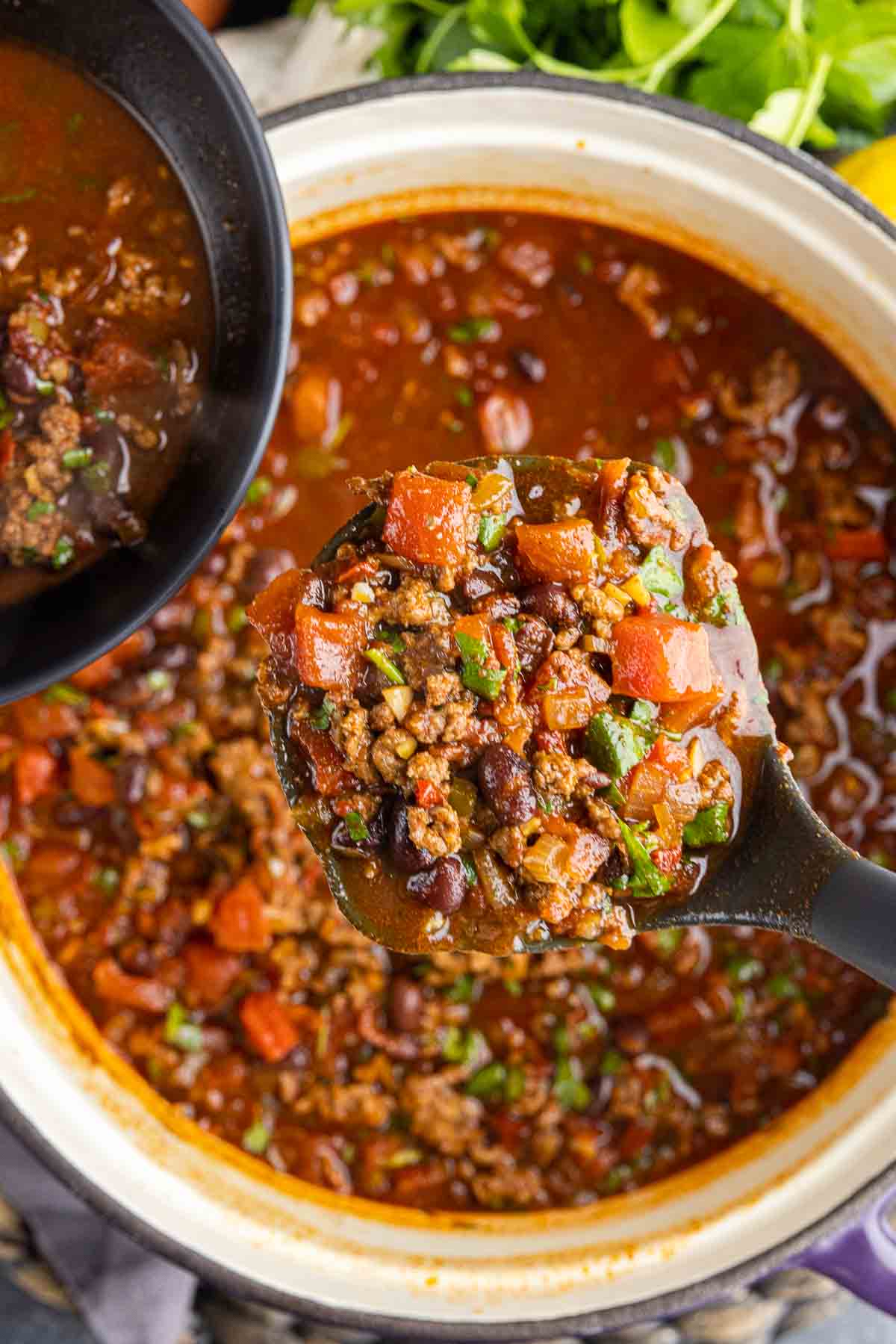 scooping Smoky Chipotle Chili into a black bowl