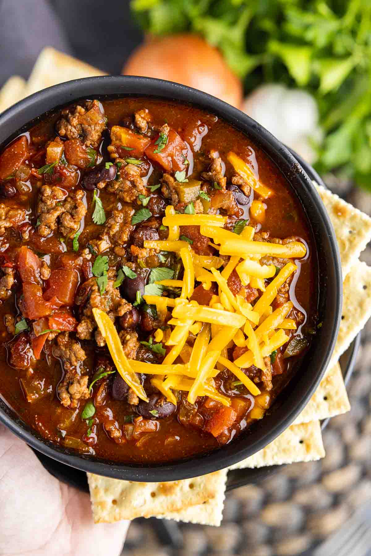 holding a bowl of bowl with Smoky Chipotle Chili with crackers