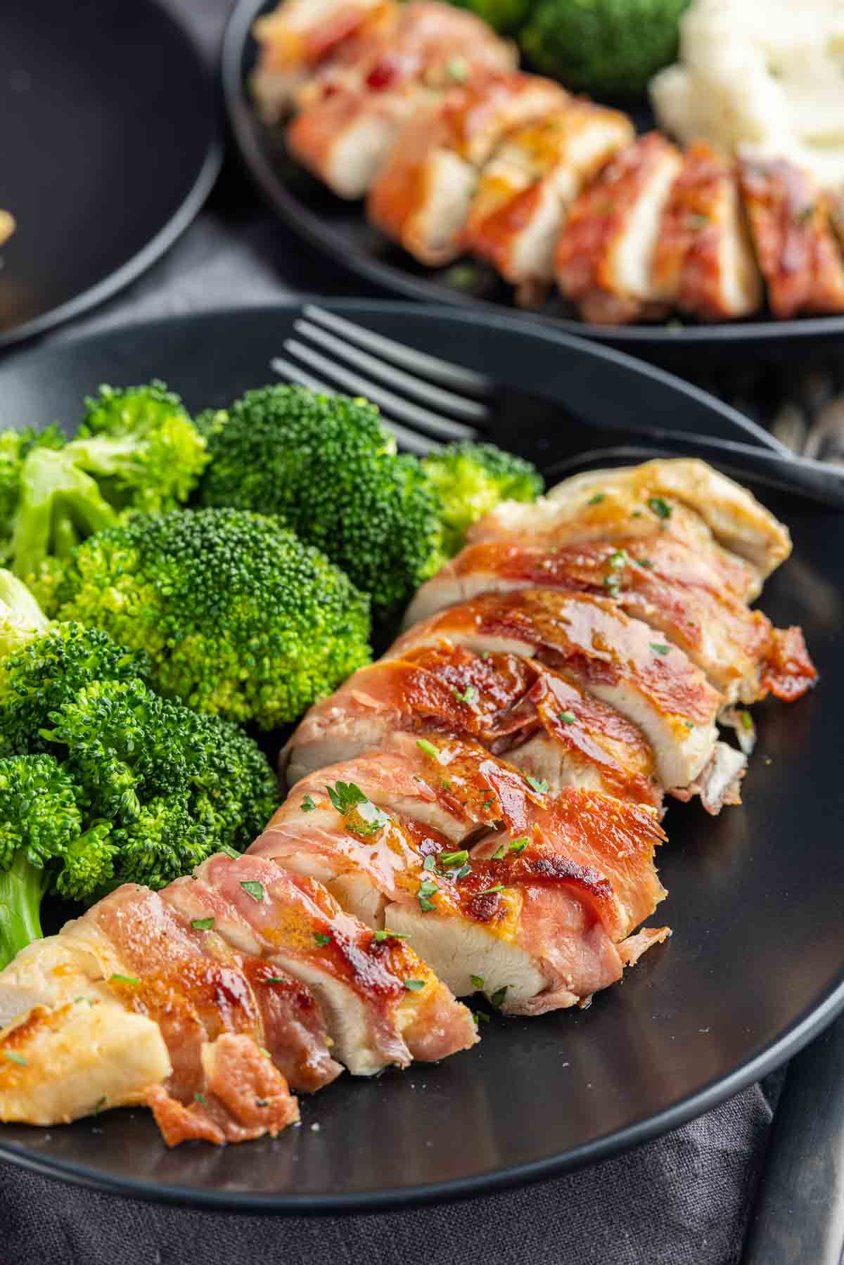 sliced up Prosciutto Wrapped Chicken on a plate with broccoli