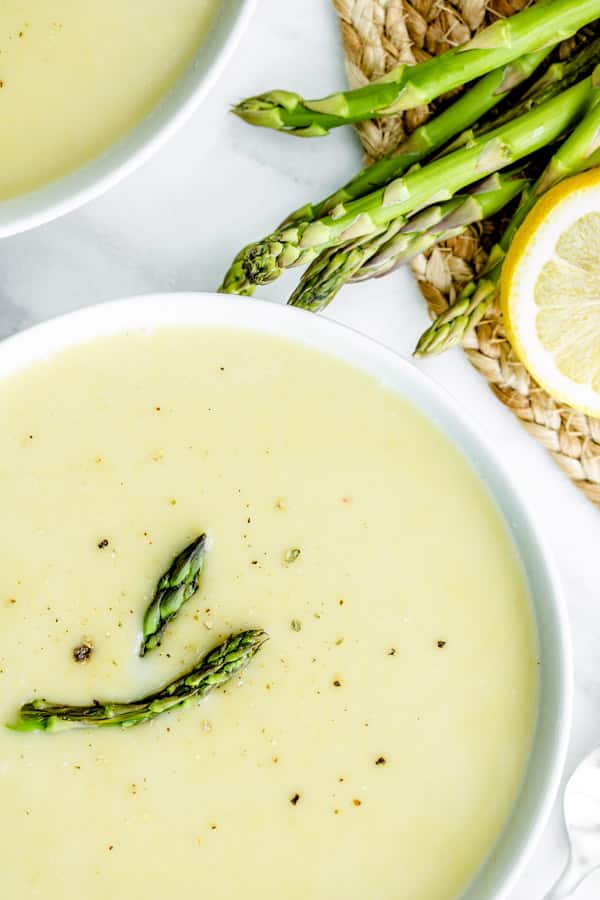 Asparagus Soup in a bowl with asparagus and lemon slice