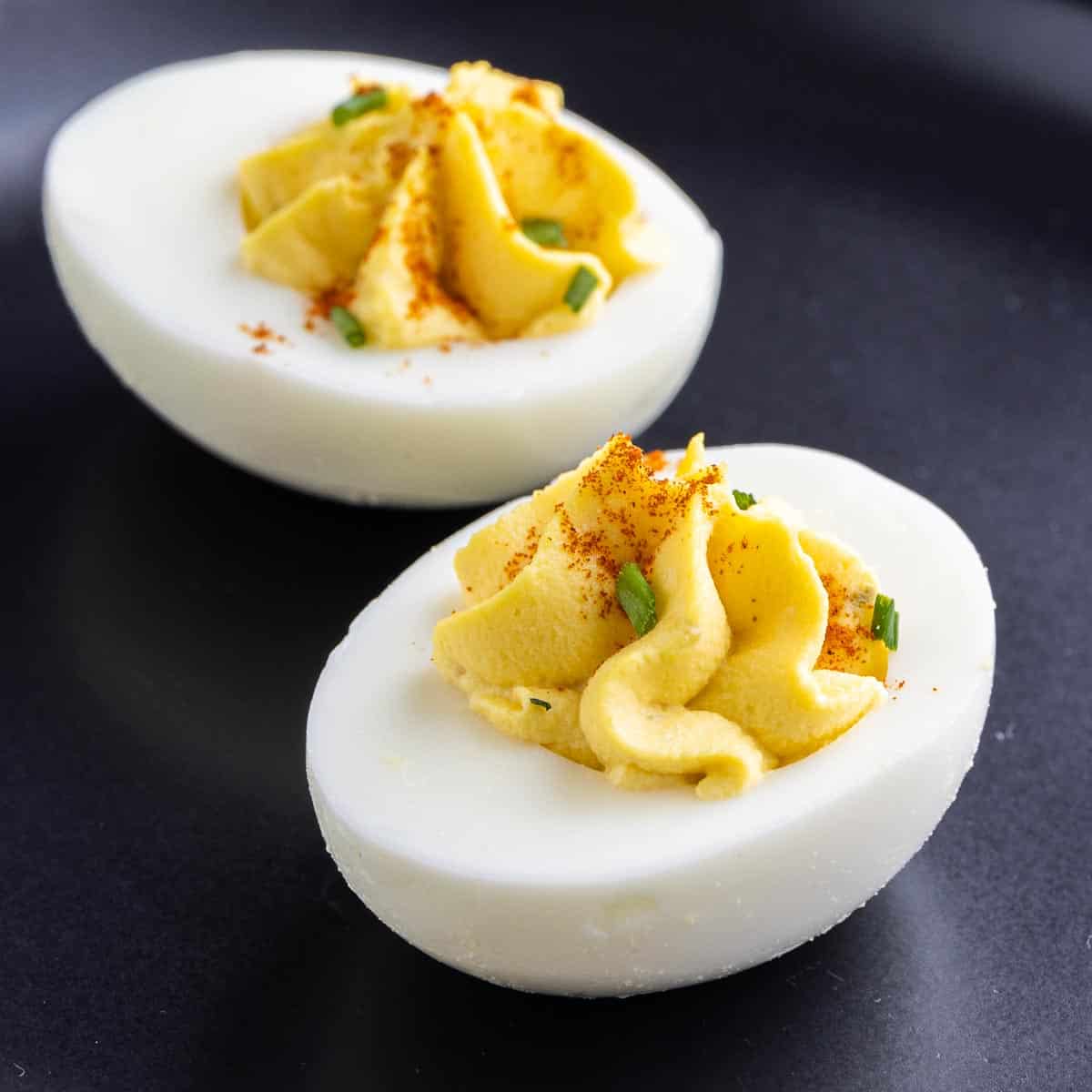 two Southern Deviled Eggs on a black plate