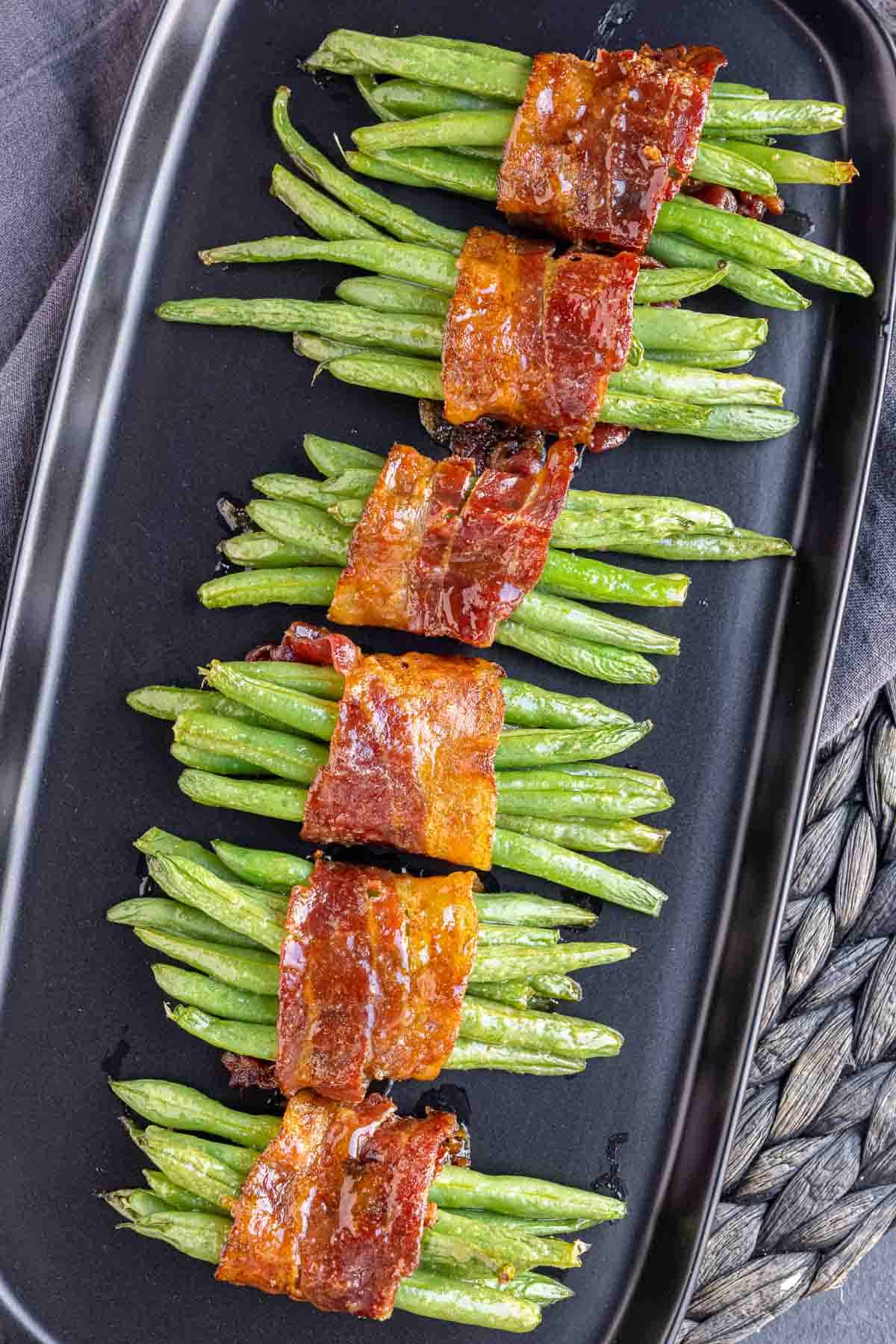 bundles of Bacon Wrapped Green Beans lined up on a black platter