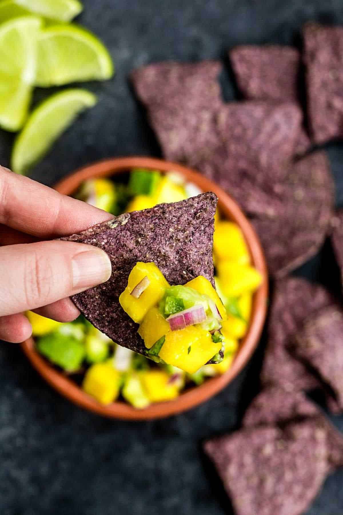 holding a chip with Mango Salsa