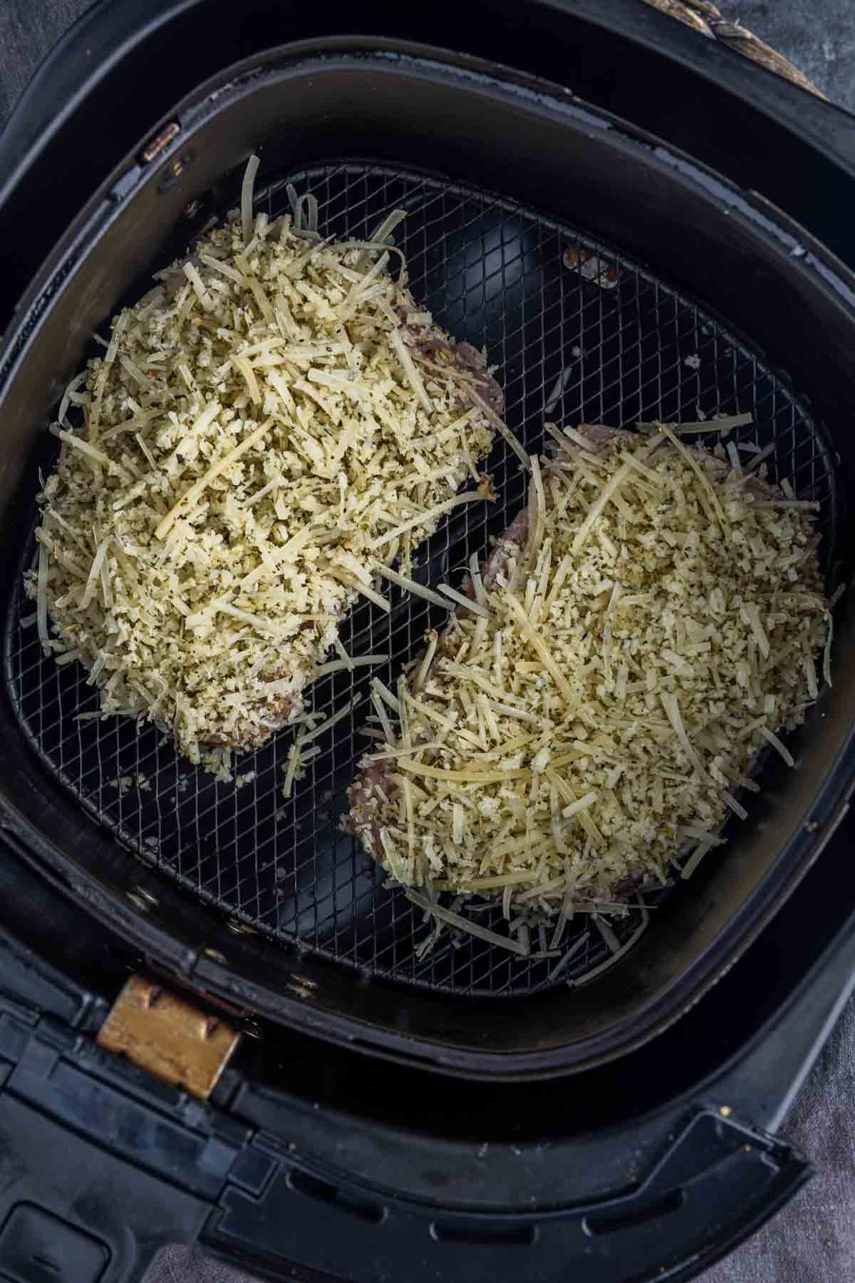 two raw Air Fryer Parmesan Crusted Pork Chops in air fryer basket