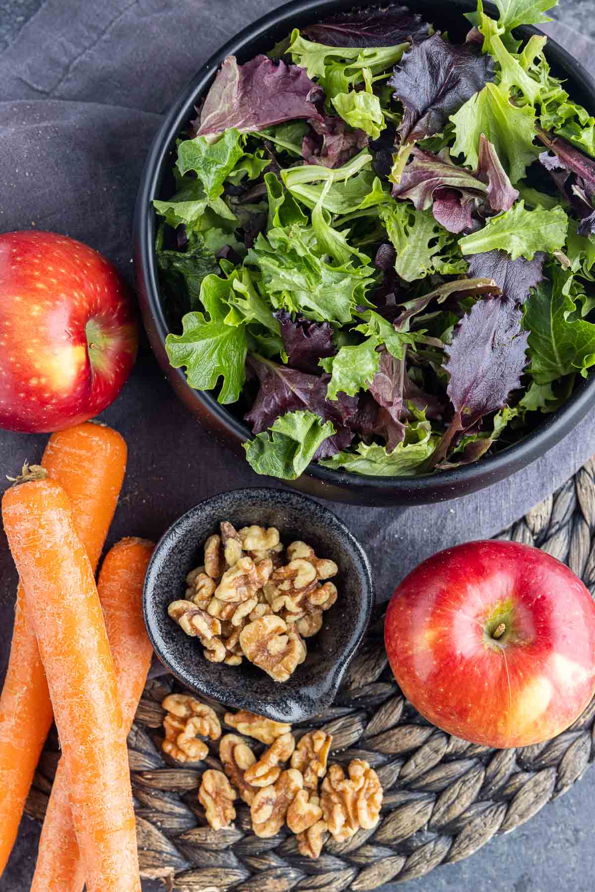 apples, carrots, walnuts and greens in a bowl to make Apple Walnut Salad