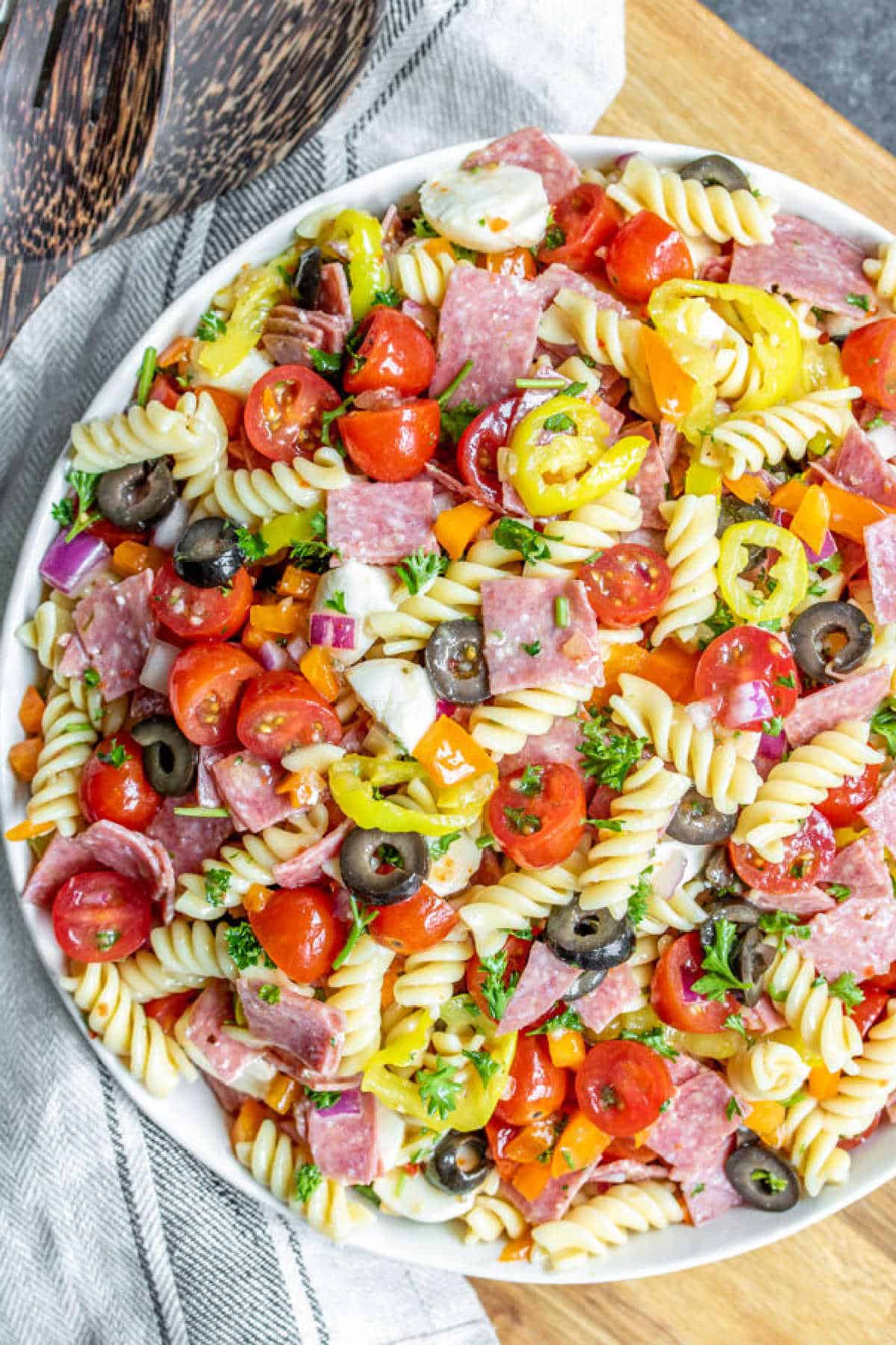 Italian Pasta Salad in a bowl with wooden spoon and linen cloth