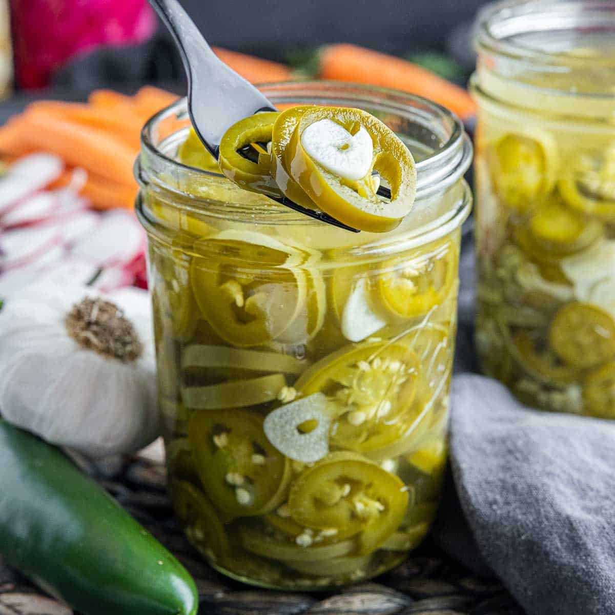 Pickled Jalapenos on top of a jar on a fork