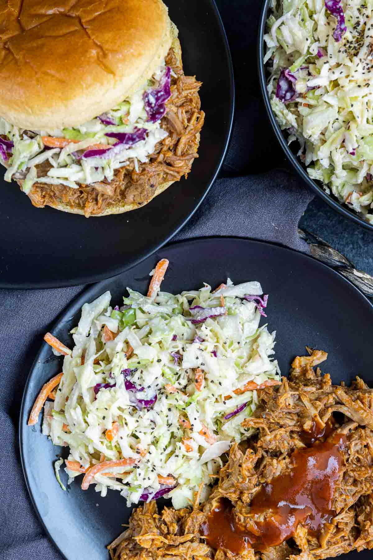 Southern Coleslaw on a black plate with pulled pork sandwich